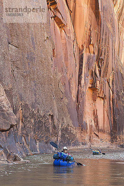 Menschen paddeln auf Packrafts unterhalb hoher Klippen auf dem Escalante River  Utah