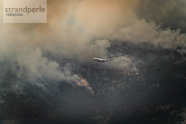 Flugzeug fliegt über Flächenbrand im Wald
