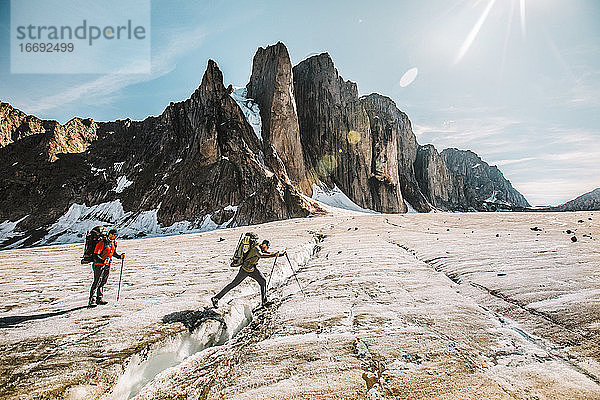 Ein Bergsteiger überquert an einem sonnigen Tag eine Gletscherspalte  Baffin Island.
