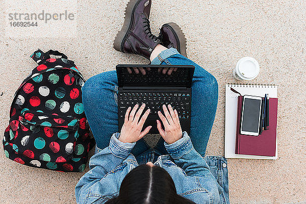 Draufsicht auf eine Studentin beim Schreiben auf ihrem Laptop