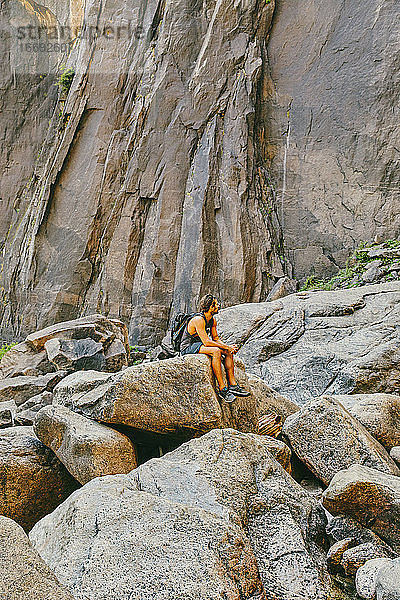 Junger Mann ruht sich auf einem Felsen aus und beobachtet die Yosemite Falls.