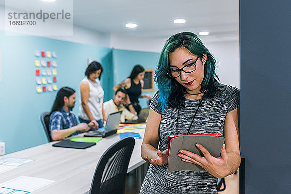 Eine Geschäftsfrau benutzt ein Tablet in einem Coworking-Büro