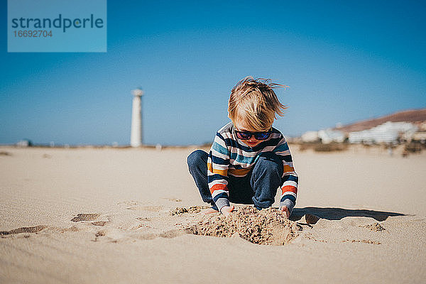 Junge Kind Kind spielt am Strand an einem kalten und windigen Tag