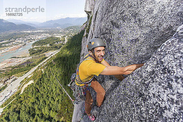 Mann schaut in die Kamera beim Klettern einer Mehrseillängenroute auf Granit Squamish