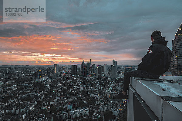 Circa Juni 2018: Person sitzt auf Dachkante mit Blick auf Stadtbild von Frankfurt am Main  Deutschland Skyline bei Nacht