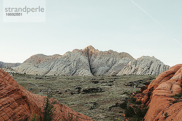 Wüstenlandschaft mit roten Felsen  weißen Klippen und grünem Tal in Utah