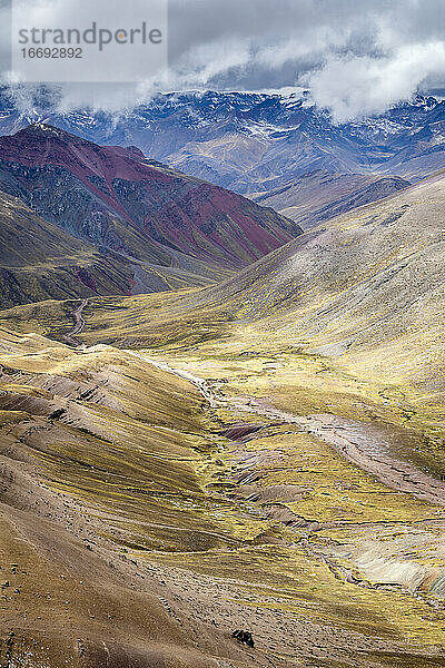 Panoramablick auf ein Tal inmitten hoher Andenberge auf dem Rainbow Mountain Trail  Pitumarca  Peru