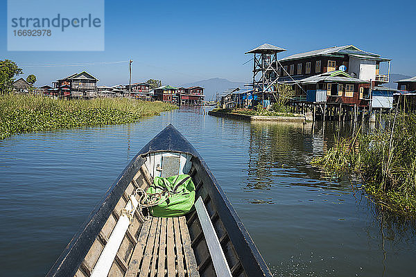 Dorf am Inle-See vor blauem Himmel vom Motorboot aus gesehen  Myanmar