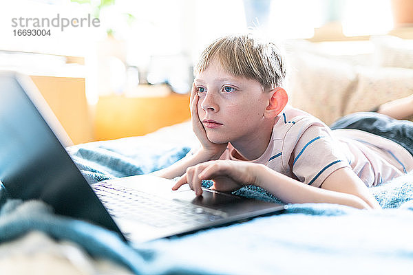 Tween arbeitet am Laptop und sieht gelangweilt aus  wenn sie an einem sonnigen Tag zu Hause ist