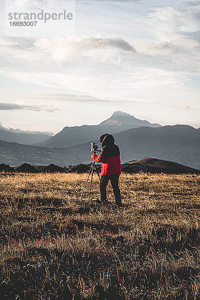 Fotograf beim Fotografieren in den Bergen mit Bergen im Hintergrund