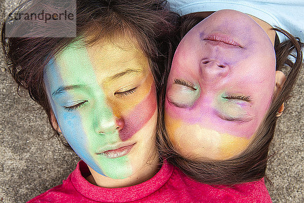 Zwei friedliche Kinder mit geschminkten Gesichtern liegen mit geschlossenen Augen zusammen