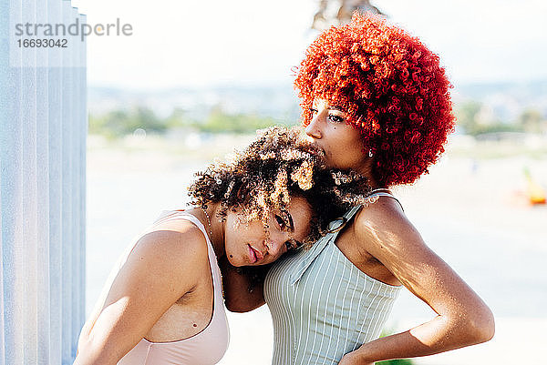 Zwei attraktive Latino-Mädchen mit Afro-Haar in einer Haltung der Liebe.