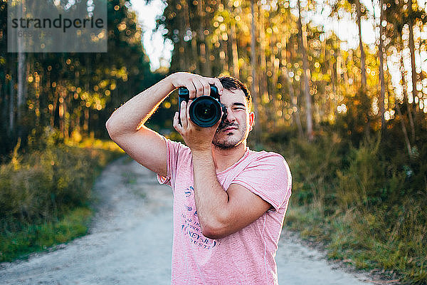 Porträt eines jungen Mannes  der mit einer Kamera fotografiert