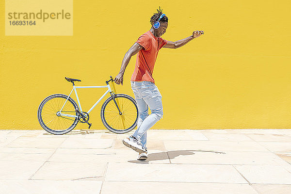 Energetischer ethnischer Mann springt in der Nähe von Fahrrad