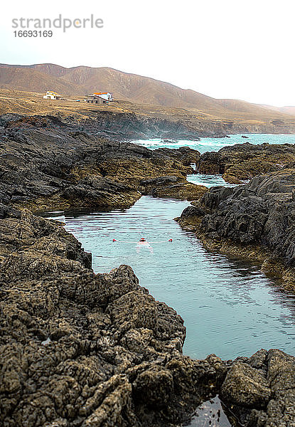 Mann beim Schwimmen und Entspannen im natürlichen Meeresschwimmbad auf der Insel Fuerteventura.