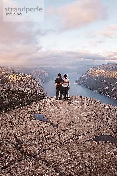 Stehendes und einander zugewandtes Paar auf der Klippe am Preikestolen  Norwegen  bei Sonnenuntergang