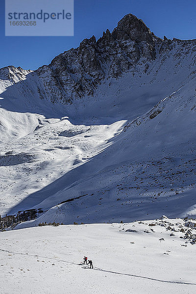 Zwei Personen gehen in Colorado zwischen zerklüfteten Gipfeln Ski fahren.