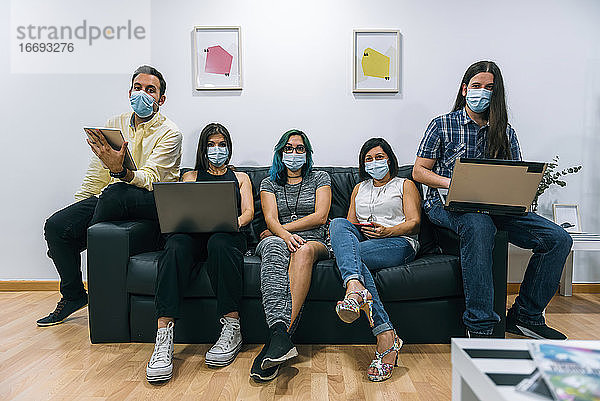 Gruppe junger Leute mit Masken während einer Pause in einem Coworking-Büro.