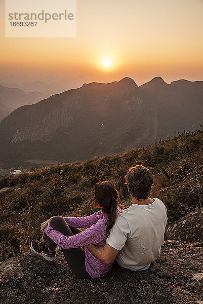 Schöne Aussicht auf ein wanderndes Paar  das den Sonnenuntergang vom Berggipfel aus genießt