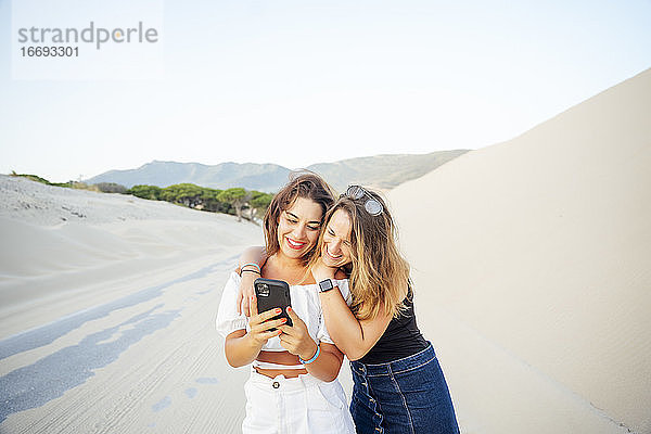 Junge Frauen mit Mobiltelefonen sind begeistert und glücklich