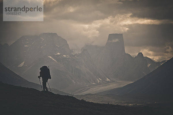 Silhouette eines Rucksacktouristen  der durch eine zerklüftete Berglandschaft wandert