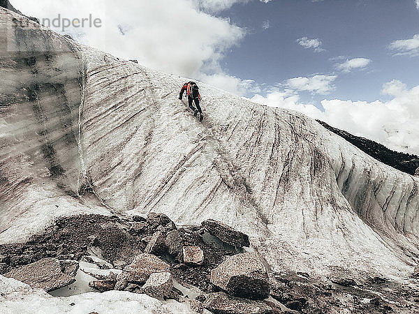 Bergsteiger klettert an einer Eiswand neben einem fließenden Schmelzwasserfluss