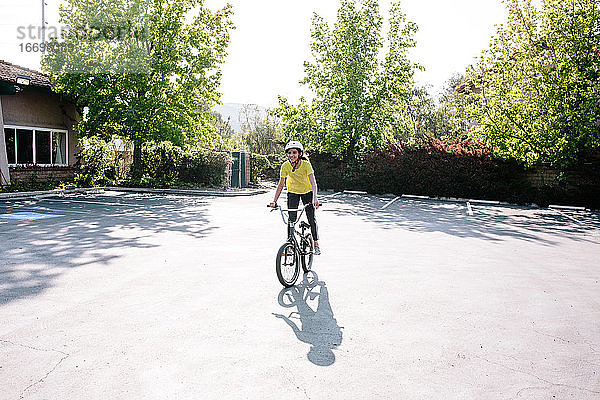 Tween Mädchen steht lächelnd auf den Pedalen ihres Fahrrads