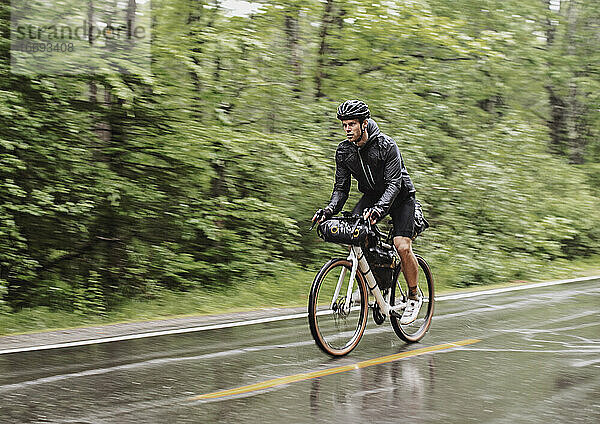 nasser und durchnässter Radfahrer fährt im strömenden Regen auf der Straße in Boothbay Maine