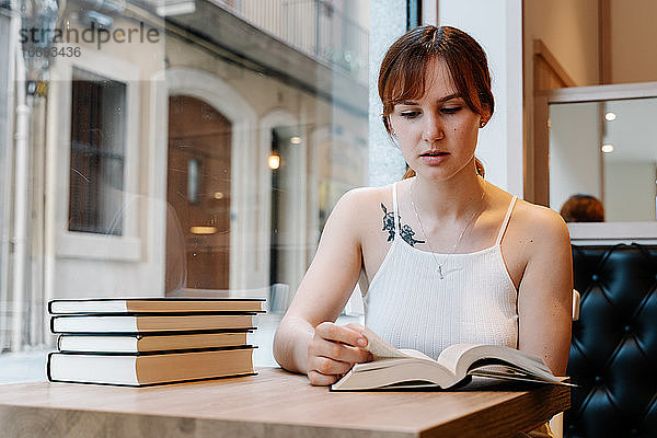 Junge Frau liest Bücher in einem Café