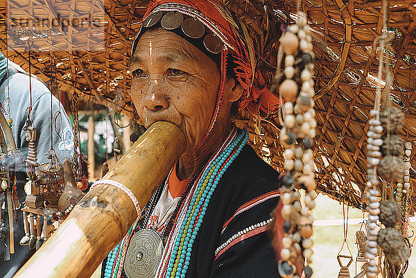 Porträt einer Frau aus einem thailändischen Volksstamm  die ein Musikinstrument spielt.