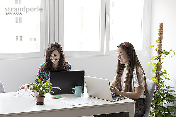 Fröhliche Frauen mit Laptops im Büro