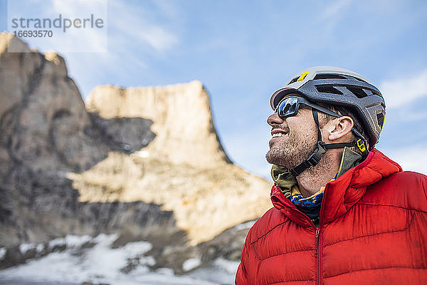 Lächelndes Porträt eines Bergsteigers in der Seitenansicht unterhalb des Gipfels.