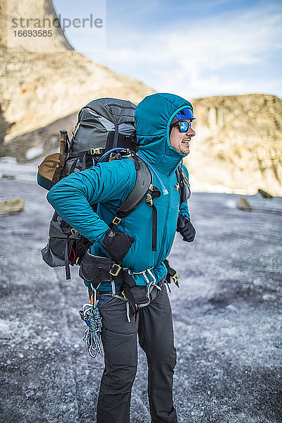 Ein Bergsteiger schnallt sich auf einer mehrtägigen Tour einen schweren Rucksack um.