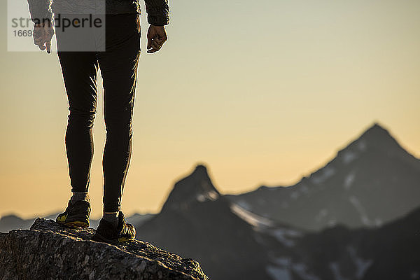 Untere Hälfte des Trailrunners auf dem Berggipfel stehend mit Aussicht