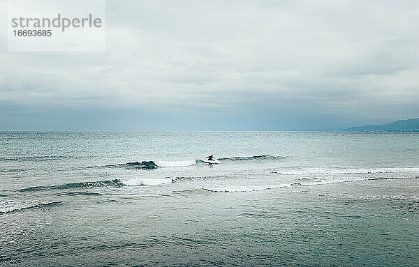 Silhouette in der Mitte eines Mannes Surfen im Meer in der Nähe der Küste