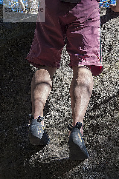 Die Beine eines Kletterers  der sich am Felsen festhält.