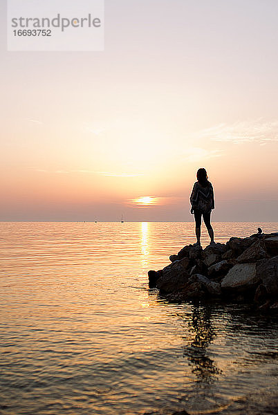 Frau Silhouette stehend auf Felsen am Meer