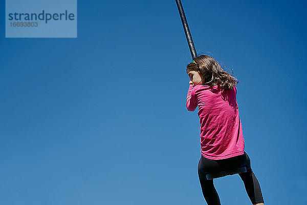 Mädchen auf einer Kinder-Seilrutsche mit blauem Himmel im Hintergrund