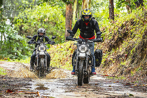 zwei Freunde fahren mit ihren Scrambler-Motorrädern durch den Wald