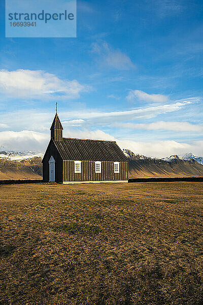Schwarze Holzkirche Budakirkja vor schneebedeckten Bergen  Budir  Halbinsel Snaefellsness  Island