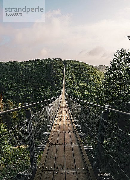 Braune hölzerne Hängebrücke im immergrünen tropischen Wald über dem Kopf