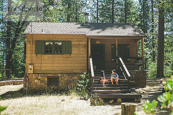 Kinder sitzen auf der Veranda einer Hütte im Wald