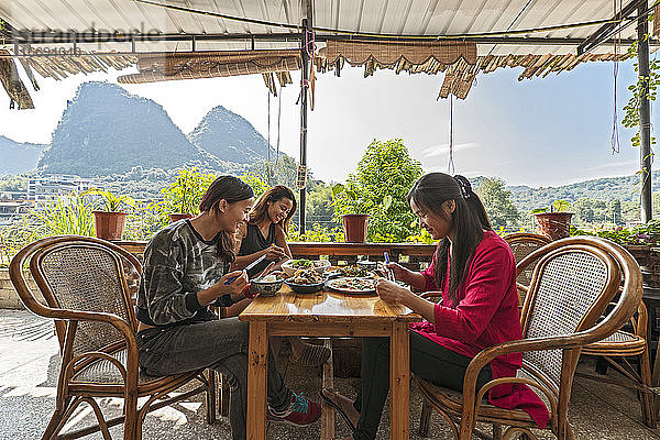 drei Freundinnen beim Mittagessen auf der Terrasse