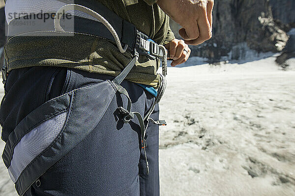 Ein Bergsteiger zieht vor dem Klettern seinen Klettergurt an.