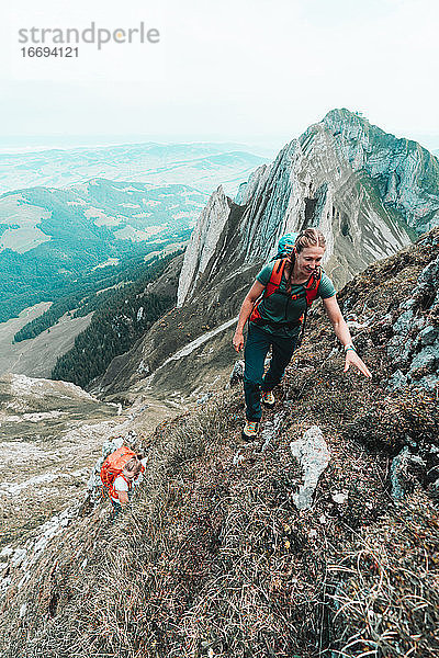 Zwei Bergsteigerinnen besteigen einen steilen Berg in der Schweiz