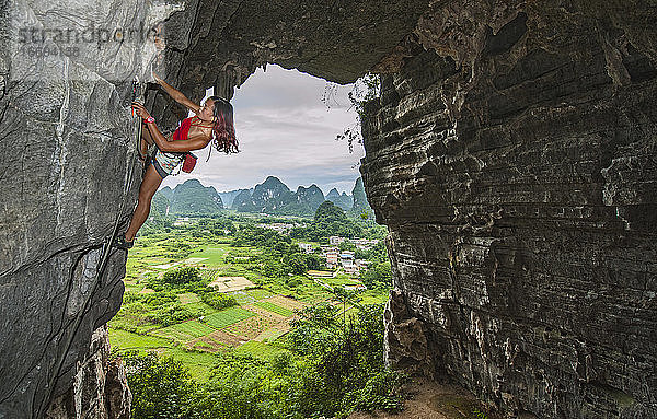 junge Bergsteigerin beim Klettern in der Schatzhöhle in Yangshuo  China