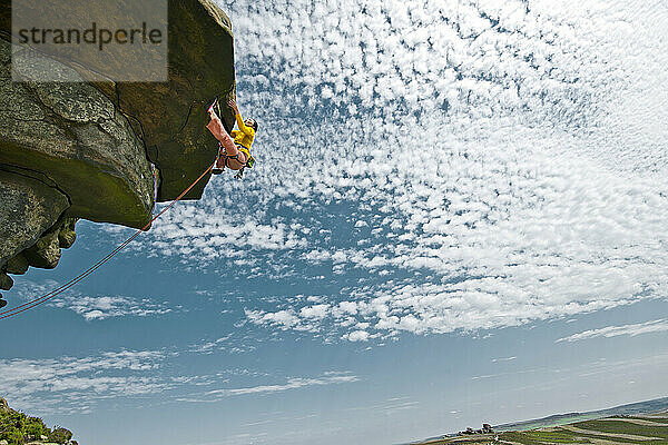 Frau beim Klettern an den Windgather-Felsen im britischen Peak District