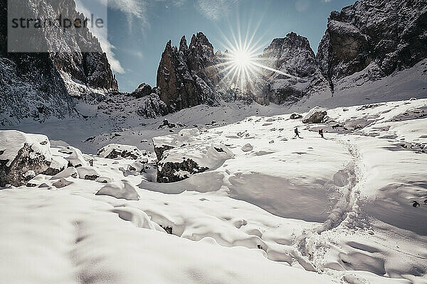 Zwei Wanderer beim Abstieg vor steilen Dolomitengipfeln unter blauem Himmel