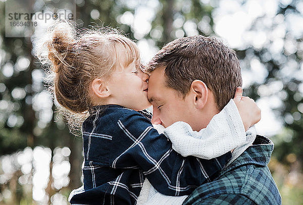 Tochter küsst den Kopf ihres Vaters und sieht zufrieden und glücklich aus