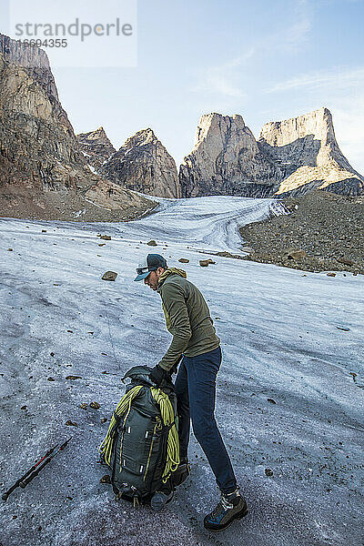 Rucksacktourist packt seine Tasche auf dem Gletscher unterhalb des Mount Asgard.